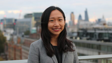 Headshot of Bonnie Chiu: a young Chinese woman with long dark hair wearing a black top and grey blazer.