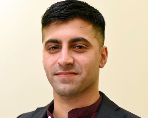 Headshot of young man with dark hair smiling.