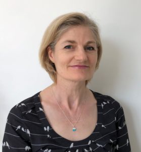 Headshot of white, middle-aged woman with short blonde hair and silver chain necklace.