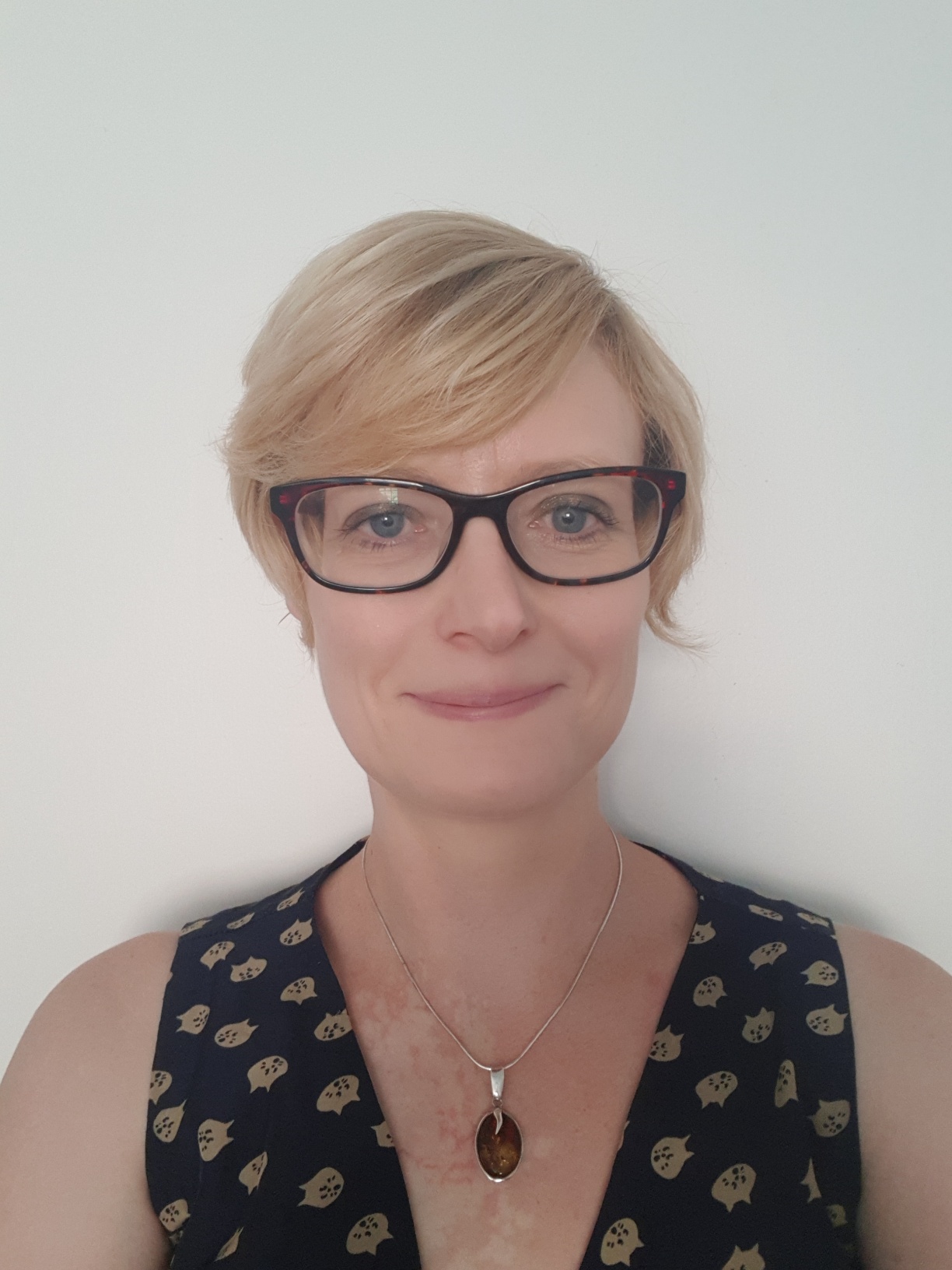 Headshot of white, middle aged woman wearing glasses with short blonde hair.