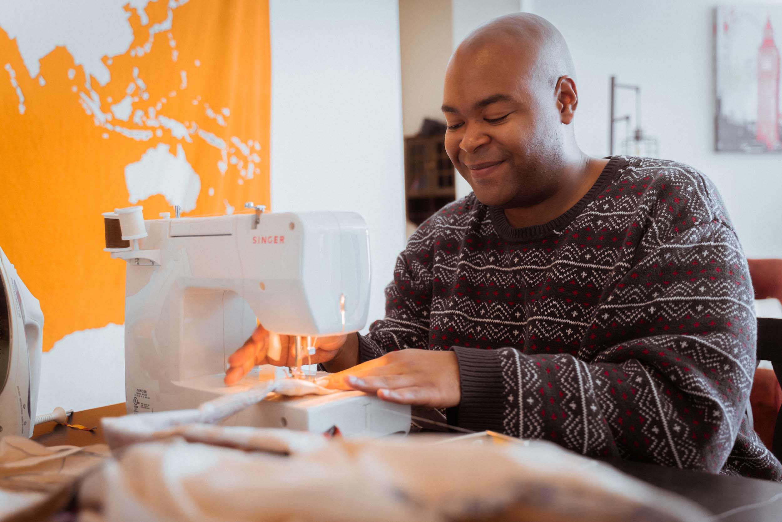 Smiling black dressmaker working on a sewing machine. 