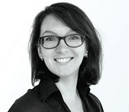 Black and white headshot of smiling young woman with brown short hair wearing glasses